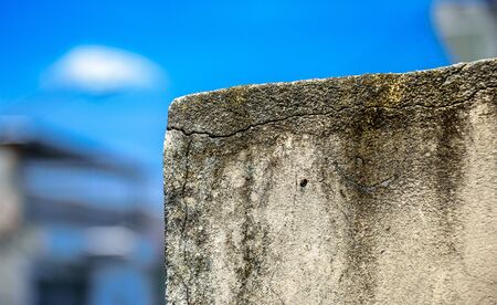 The moldy wall on the background of blurry buildings and bright blue sky at sunny summer dayの写真素材