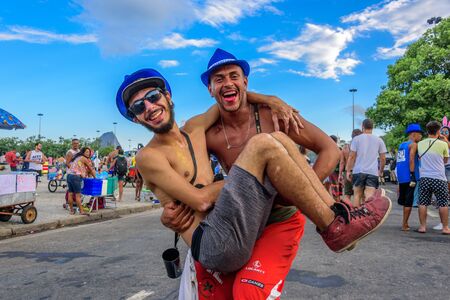 RIO DE JANEIRO, BRAZIL - FEBRUARY 28, 2017: One young man holding another man up in his arms on the background of Sugarloaf Mountain during Bloco Orquestra Voadora at Aterro do Flamengo, Carnaval 2017のeditorial素材