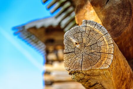 Details of log cabin corner joint with round logs and blurry roof of wooden house on the background at sunny spring day, Moscow, Russiaの写真素材