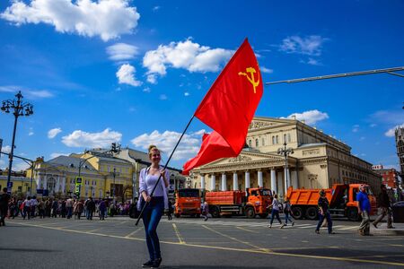 MOSCOW, RUSSIA - MAY 01, 2017: Young woman staying on the background of the Bolshoi Theatre at International Workers' Day with a big red flag of the USSR with Hammer and Sickleのeditorial素材