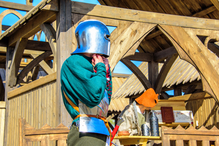 The knight wearing helmet and armor on the background of wooden castle at the international knight festival Tournament of Saint George in the Kolomenskoye museum-reserveの写真素材