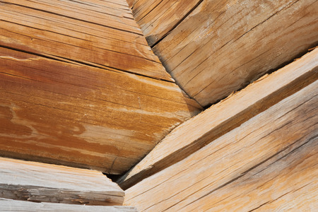 Closeup of joint of round very cracked logs of old wooden building at sunny dayの写真素材