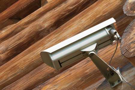 Bottom view of video camera screwed to the corner of the log house and the small loophole in the...