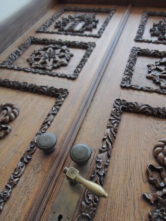 antique solid wood door with carved ornaments and a bronze handleの写真素材