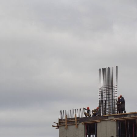 A fragment of the concrete structures and steel reinforcement being erected in a multi-storey building at the construction stage, without walls and windows. Side view. With text box area.の写真素材