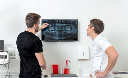 Two Doctors of Dentistry reviewing a panoramic x-ray of a dentureの写真素材