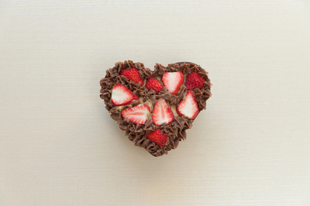 Heart shaped chocolate cake with strawberries. Celebration for Valentine's Day or Mother's Day. Isolated on beige background. Top view. Space for text.の写真素材