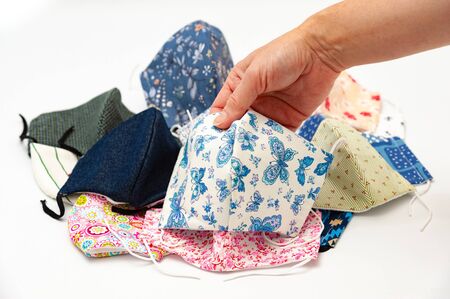 Hand holding (DIY) homemade surgical face mask in blue and white colors for protection against...