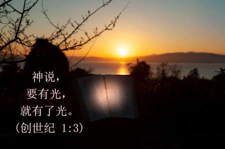 Holy Bible opened with directional light. Background with sea, golden sky and sunrise behind the...