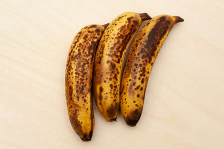 Three ripe bananas isolated on light wooden background. Top view. Copy space.の写真素材