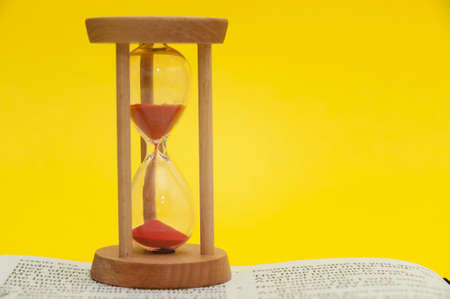 Red sand hourglass on top of open Holy Bible in the Book of the Prophet Ezekiel chapter 7 verse 7....
