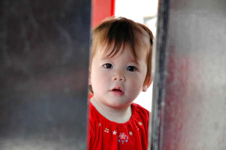Beautiful Asian baby girl wearing red clothes staring at the camera. Horizontal shot.