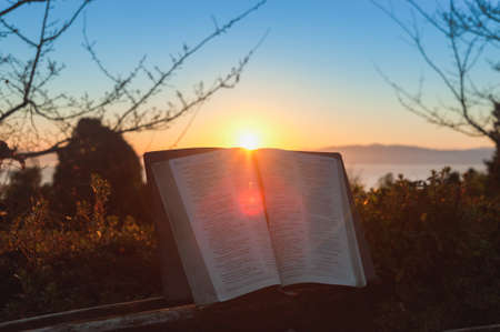 Open bible at sunrise with flare in Fuji city, Japan. Background with sea, mountain and blue sky.の写真素材