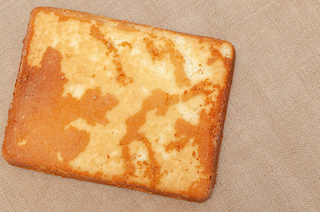 Homemade Sponge Cake, in Portuguese Pao de Lo. Bottom part of the baked cake dough. Isolated on jute background. Top view. Copy space. Horizontal shot.の写真素材