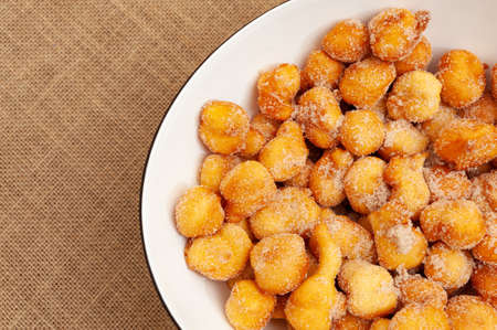 Delicious and traditional homemade Brazilian sweet called "Bolinho de Chuva" on a plate. Isolated on jute background. Top view. Copy space.の写真素材