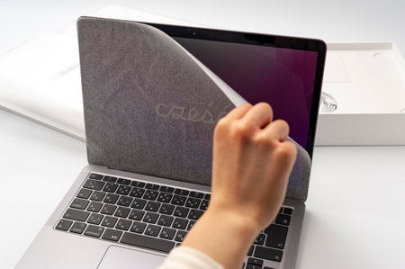 Fuji-shi, Shizuoka-ken, Japan - March 11, 2022: Hand removing protective paper from MacBook Air M1 screen.のeditorial素材