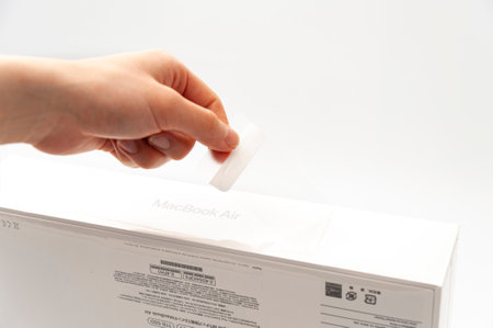 Fuji-shi, Shizuoka-ken, Japan - March 11, 2022: Hand unpacking MacBook Air M1case isolated on white background.のeditorial素材