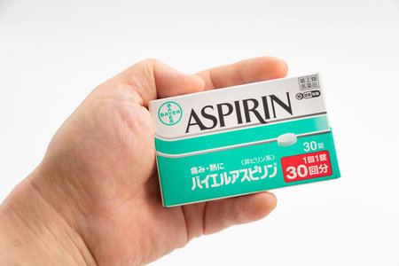 Fuji City, Shizuoka Prefecture, Japan - April 23, 2024: Hand holding Aspirin 30 tablets by Bayer Global isolated on white background.のeditorial素材