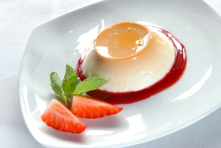 Panna-cotta with a strawberry on a white plateの写真素材