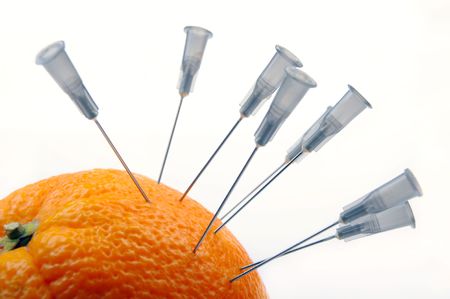 Needles from a syringe in an orange peelの写真素材