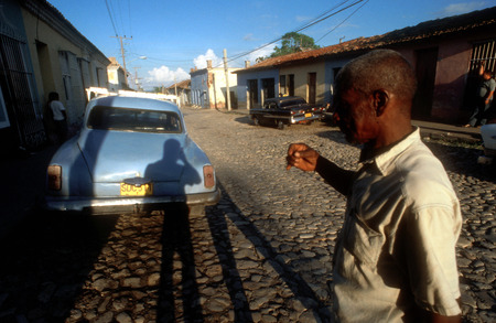 Colourful houses and people in a street scene. Classic American car parked on a street with traditional,in the background, Trinidad, Cuba, West Indies, Central Americaのeditorial素材