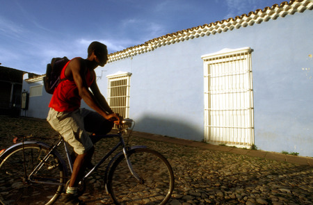 Man with a bicycle in Trinidad. Colourful houses and people in a street scene. Street scene with colourful houses, Trinidad, Cuba, West Indies, Central America.のeditorial素材