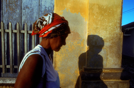 Cuban woman walking in Trinidad. Colourful houses and people in a street scene. Street scene with colourful houses, Trinidad, Cuba, West Indies, Central America.のeditorial素材