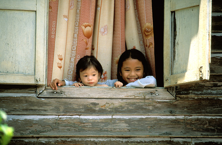 Children in a windows. Wood house. Kota Bharu, Kelantan. Malaysia.のeditorial素材
