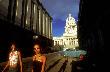 Old car 1950s Chevrolet and nice girls passing the Capitolio Nacional, Havana, Cubaのeditorial素材