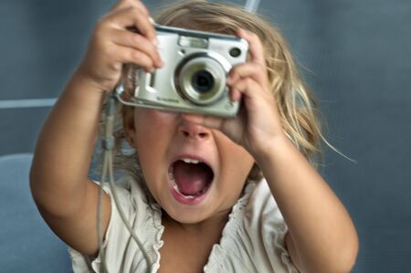 A two year old girl holding a digital snapshot camera and smiling.の写真素材