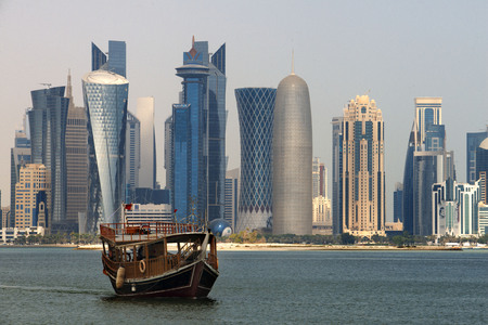 Dhow traditional sailing in Corniche promenade. Behind the skyscrapers of the skyline of the...