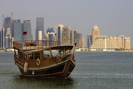 Dhow traditional sailing in Corniche promenade. Behind the skyscrapers of the skyline of the financial area of Doha, the capital of Qatar in the Arabian Gulf countryのeditorial素材