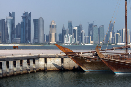 Dhow traditional sailing in Corniche promenade. Behind the skyscrapers of the skyline of the...