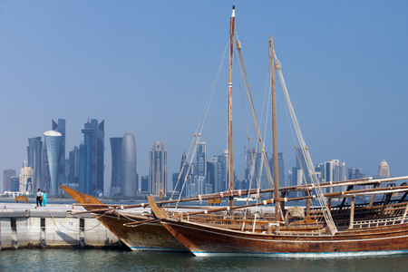 Dhow traditional sailing in Corniche promenade. Behind the skyscrapers of the skyline of the financial area of Doha, the capital of Qatar in the Arabian Gulf countryのeditorial素材