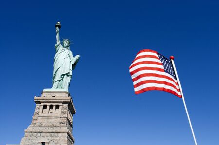 Statue of Liberty and american flag, Liberty Island, New York City, New York.の写真素材