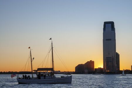 Sunset views of the Hudson River from Battery Park. A seagull just fish and the sun shines while hiding in one of the skyscrapers of Jersey.の写真素材