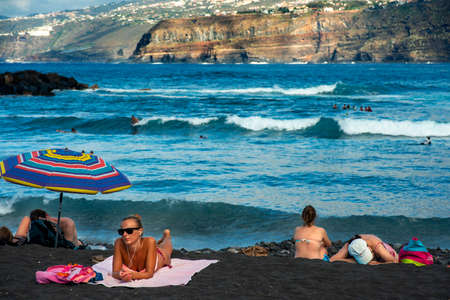 Tourists at los gigantes cliffs volcanic black sand beach in Puerto de la Cruz, Tenerife Island, Canary Islands, Spainのeditorial素材