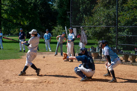 View of a baseball game in New York's Central Park through a chainmail fence. Catcher s view of baseball game Central park New York City. Central Park occupies 3.4 square kilometers and covers 50 blocks, comprised in a rectangle 4 miles long by 800 metersのeditorial素材