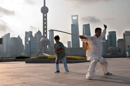 China, Shanghai, morning tai chi exercise on The Bund. Shanghi Bund : Early morning tai chi exercises with swords on the Bund in Shanghai China. The best taichi lessons I've had were from an old guy who practiced outside at 7am every morning. I learned 4 のeditorial素材