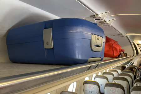 image of hand luggage on the shelf in the cabin close-upの写真素材