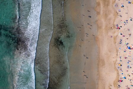 image of ocean waves, sandy beach with people bathing in the water, view from drone, Lanzada beach,...