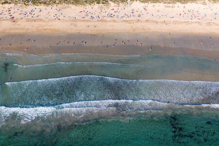 image of ocean waves, sandy beach with people bathing in the water, view from drone, Lanzada beach, Galicia, Spainの写真素材