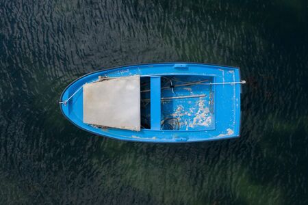 blue wooden fishing boat anchored in the sea, top view from droneの写真素材