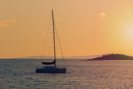 sailing yacht against sunset tinted in warm tones, beautiful natural landscape
