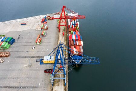 aerial view of an industrial cargo ship with containers for loading at a seaport, shot from a drone