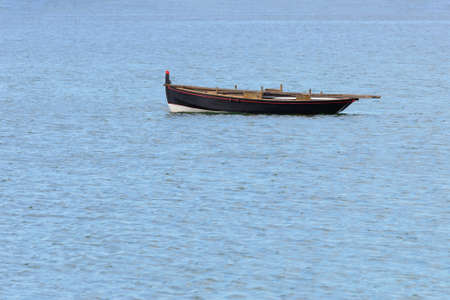 wooden fishing boat with a motor anchored in the sea, calm natural landscape