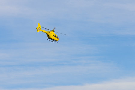 yellow helicopter flying against the blue skyの写真素材