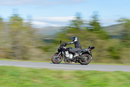 biker on a sport motorcycle rides fast while leaning on a turn on a winding road, motion blur...