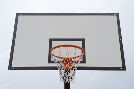 basketball backboard with a hoop and net against a blue skyの写真素材