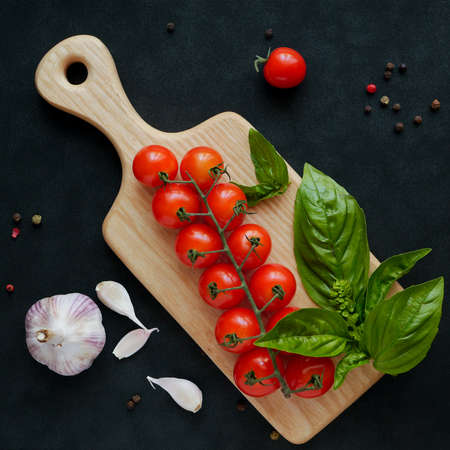 Cherry tomatoes and basil next to garlicの写真素材